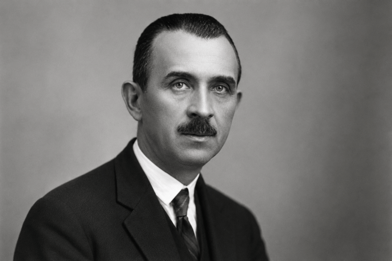 Portret alb-negru al lui Onisifor Ghibu, îmbrăcat în costum și cravată, privind către aparat.