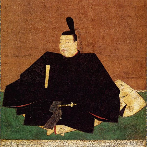 Pictură tradițională japoneză colorată pe mătase înfățișându-l pe șogunul Ashikaga Takauji așezat pe o rogojină verde, purtând haine ceremoniale negre de samurai și o tichie specifică pe cap.