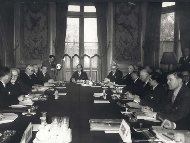Fotografie istorică alb-negru surprinzându-i pe Konrad Adenauer, Paul van Zeeland, Carlo Sforza, Joseph Bech, Dirk Stikker și Robert Schuman în timpul negocierilor pentru Tratatul de la Paris, actul de înființare a Comunității Europene a Cărbunelui și Oțelului (CECO).