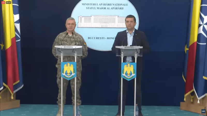 Radu Miruță și un reprezentant al Statului Major al Apărării susțin declarații de presă la sediul Ministerului Apărării Naționale, în fața drapelelor României și NATO.