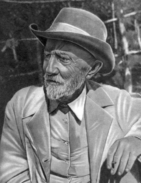 Portret fotografic alb-negru din față al botanistului Ivan Miciurin la o vârstă înaintată, purtând ochelari, bărbuță albă și o șapcă specifică pe cap.